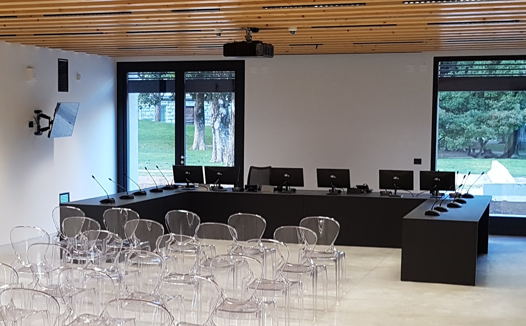 Vista frontale della sala consiliare di Torbole con banco relatori, monitor e sedie trasparenti